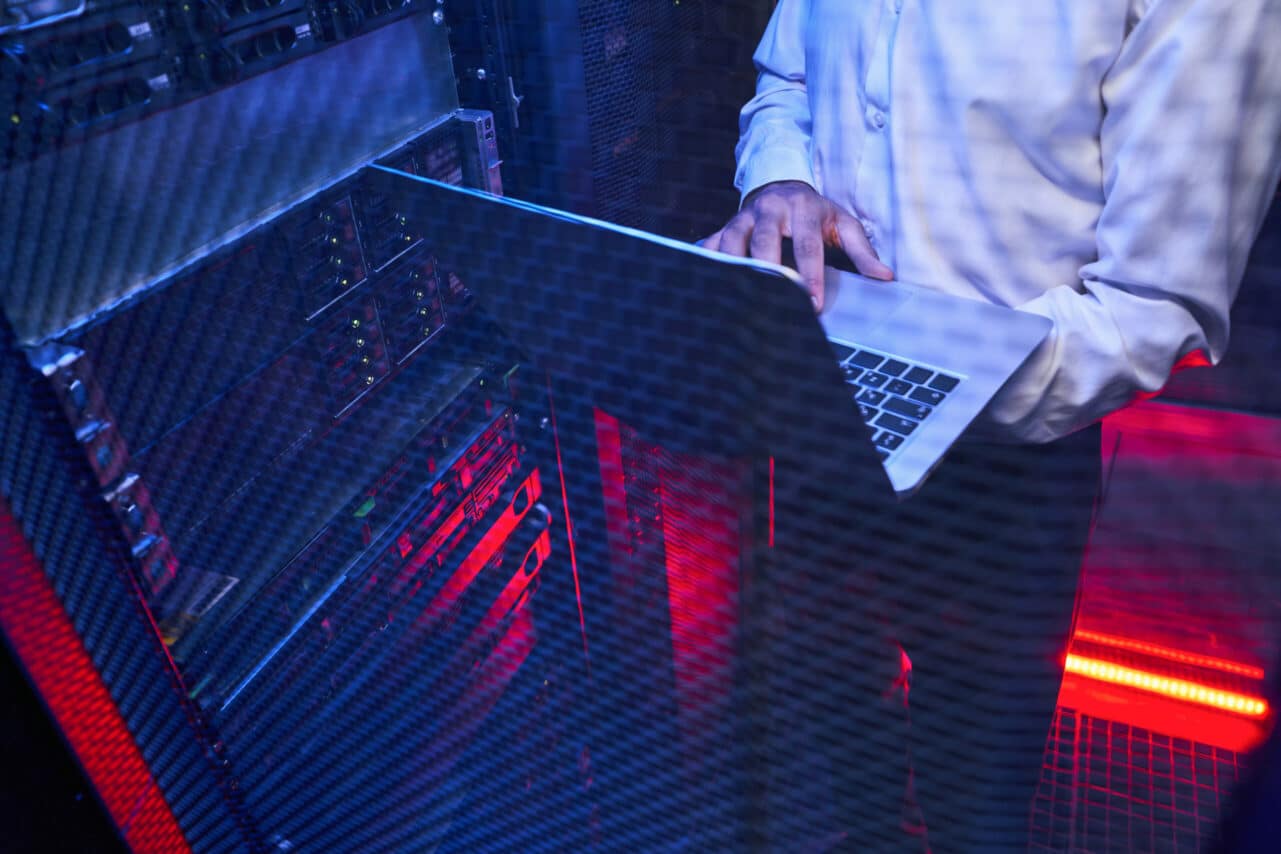 Maintenance engineer in white shirt is examining work of supercomputer in server room